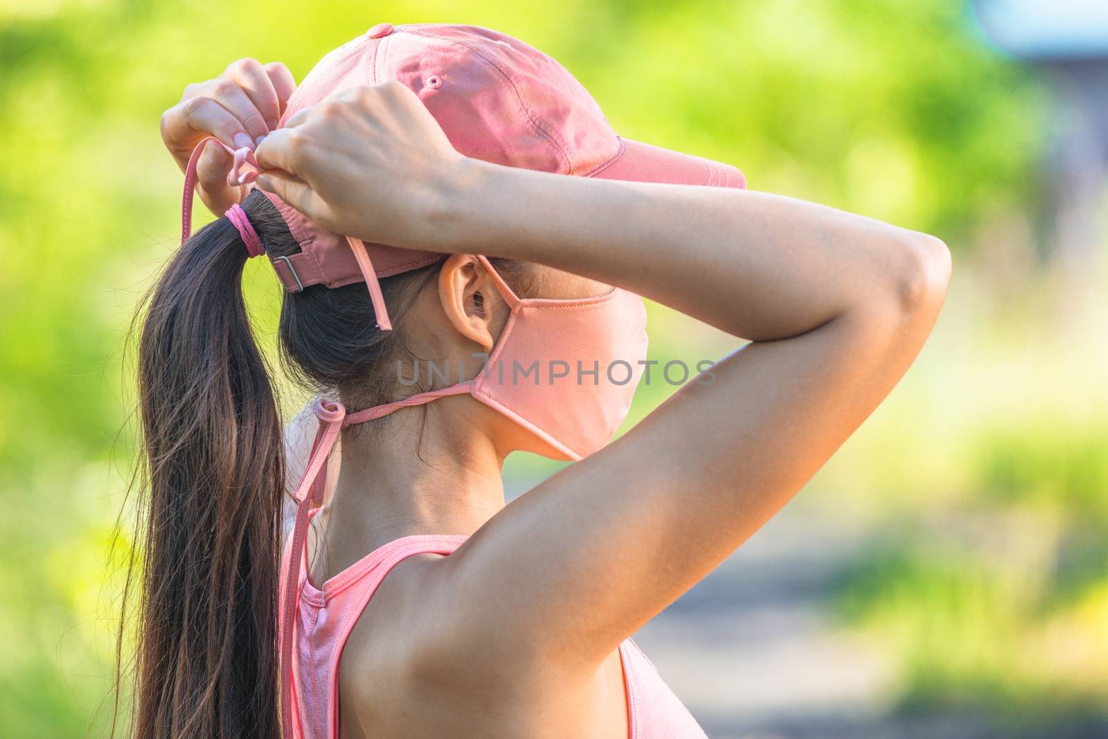 COVID-19 mask woman wearing coronavirus protection tying string ties cloth mask outside in outdoor summer park by Maridav