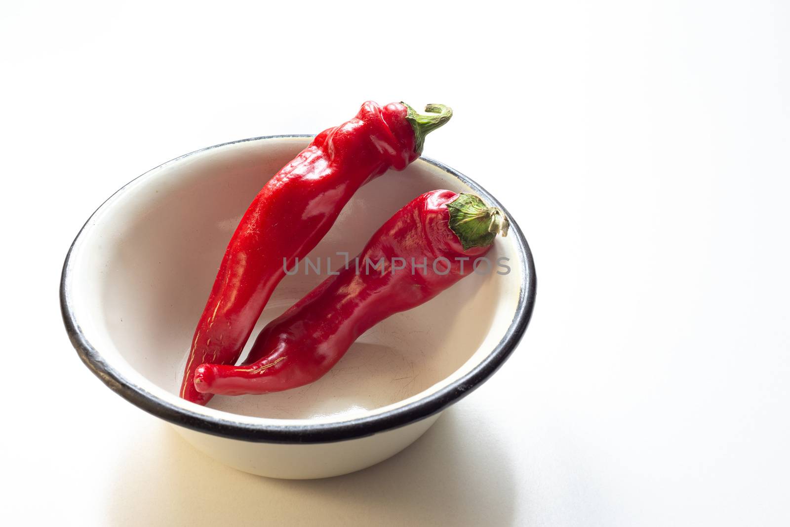 Hot red chili peppers in an enamel bowl put on a white background