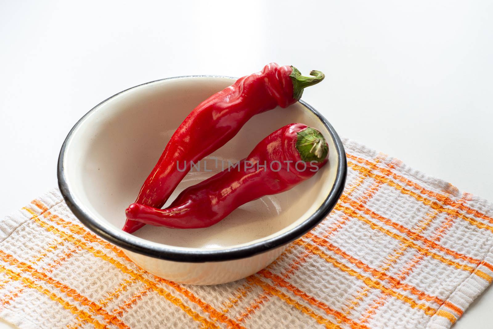 Hot red chili peppers in an enamel bowl, put on an orange and white napkin