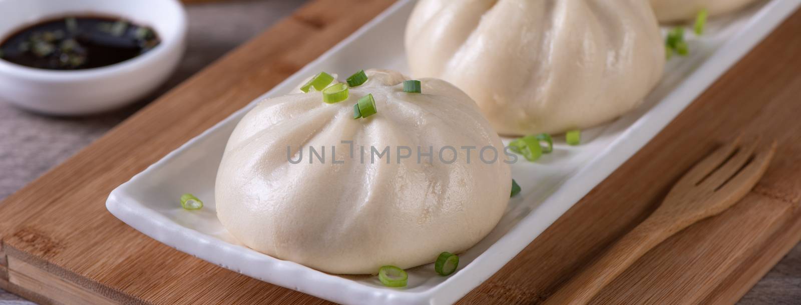 Delicious baozi, Chinese steamed meat bun is ready to eat on serving plate and steamer, close up, copy space product design concept.