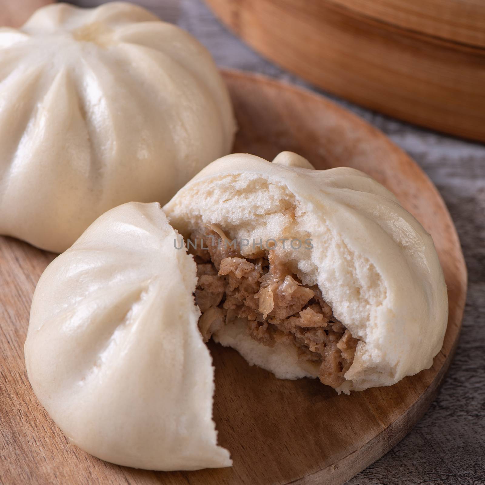 Delicious baozi, Chinese steamed meat bun is ready to eat on serving plate and steamer, close up, copy space product design concept.