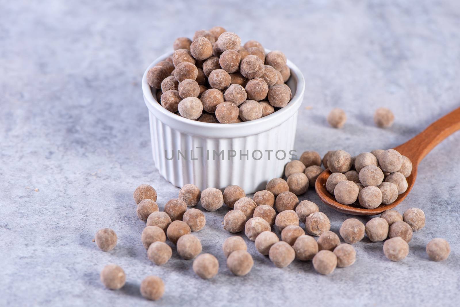 Dry raw brown tapioca pearls isolated on gray cement concrete background, close up, ingredient of making bubble boba tapioca milk tea.