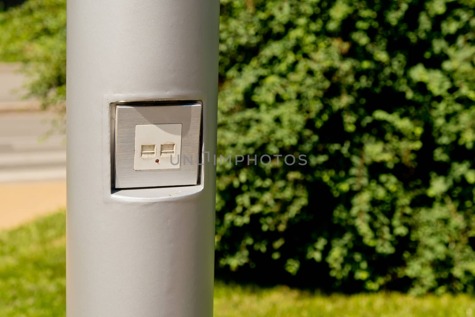 USB socket for charging mobile phones on a pole in the park.