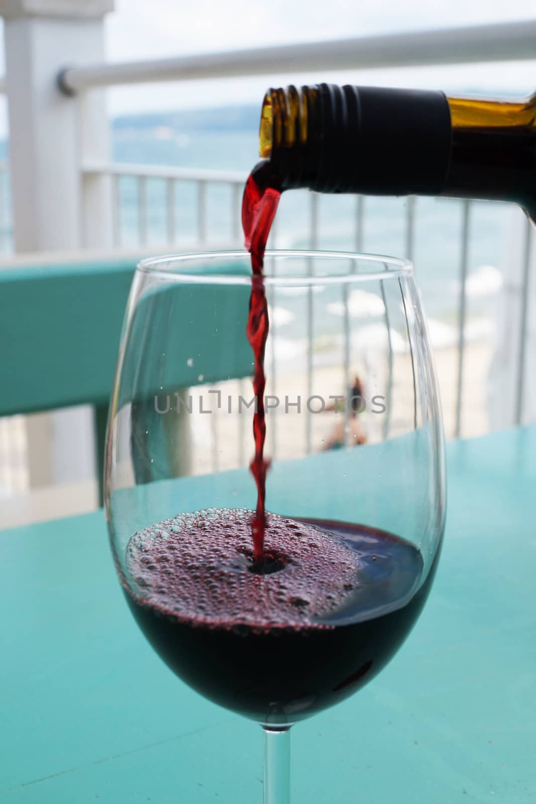 wine is poured into a glass against the background of the sea