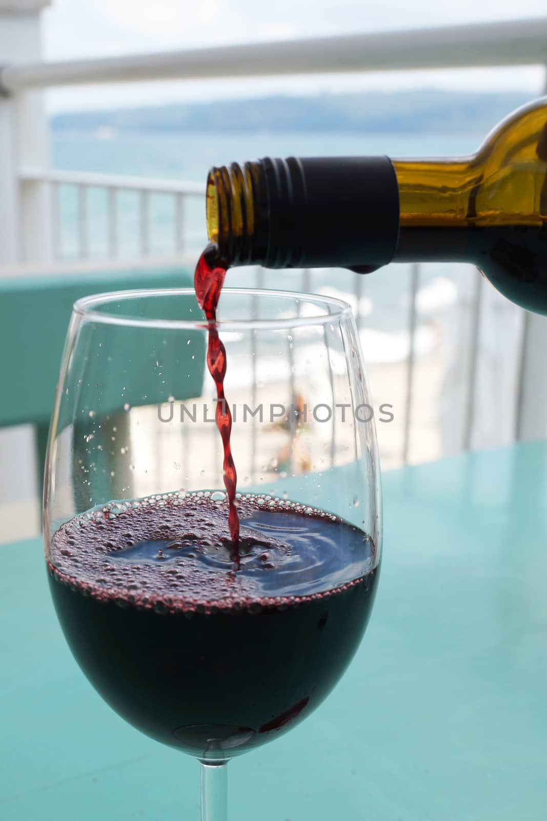 wine is poured into a glass against the background of the sea