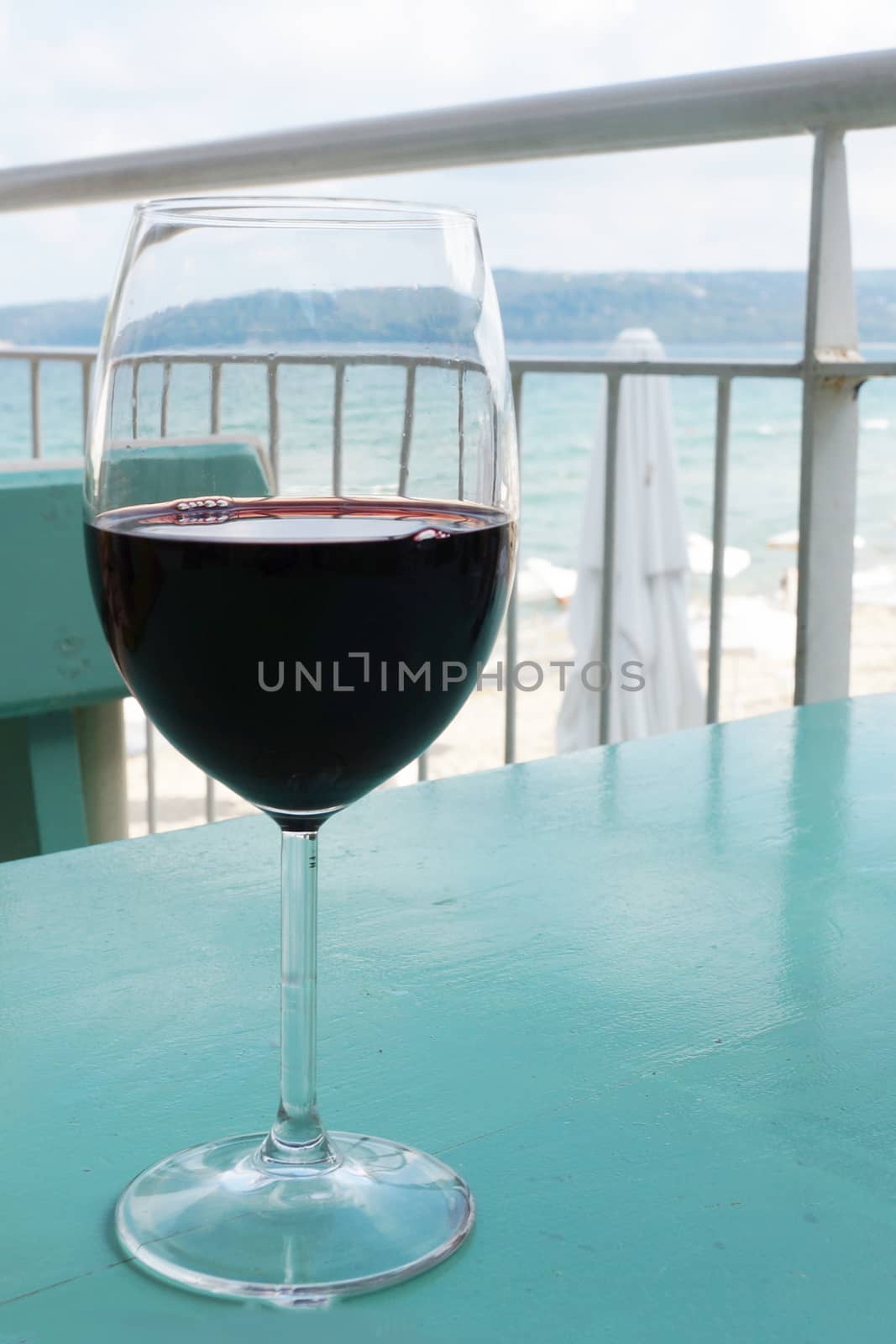 a glass of wine on a cafe table against the background of the sea.