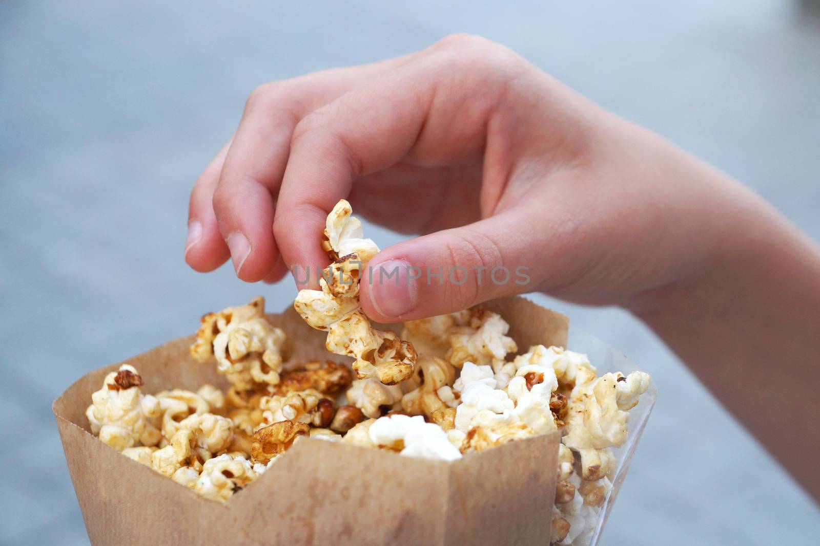 hand takes popcorn from a paper bag close up