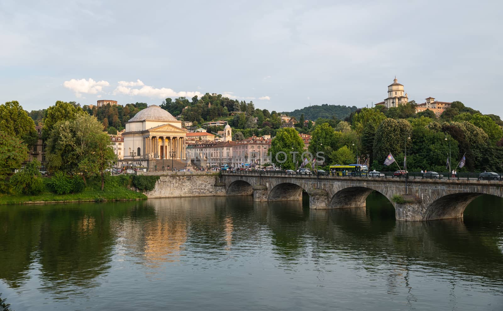 Turin, Piedmont, Italy. July 2020. Wonderful evening view of the Gran Madre church overlooking the Po river. The waterfall downstream of the dam is highlighted. On the bridge people and cars.