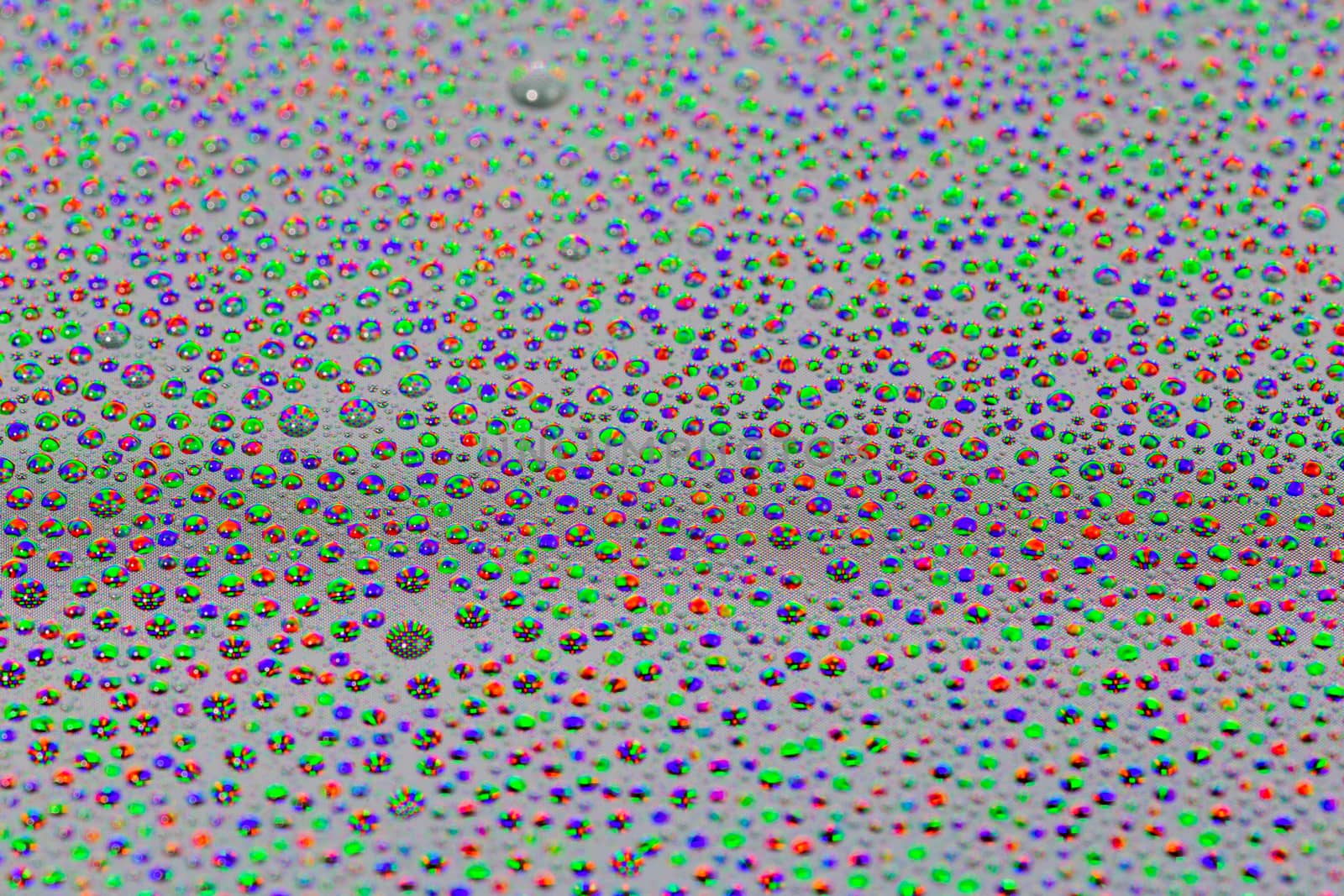 many small water drops on the surface of cellphone hydriphobic coated glass screen, close-up with selective focus and visible subpixel rgb triads