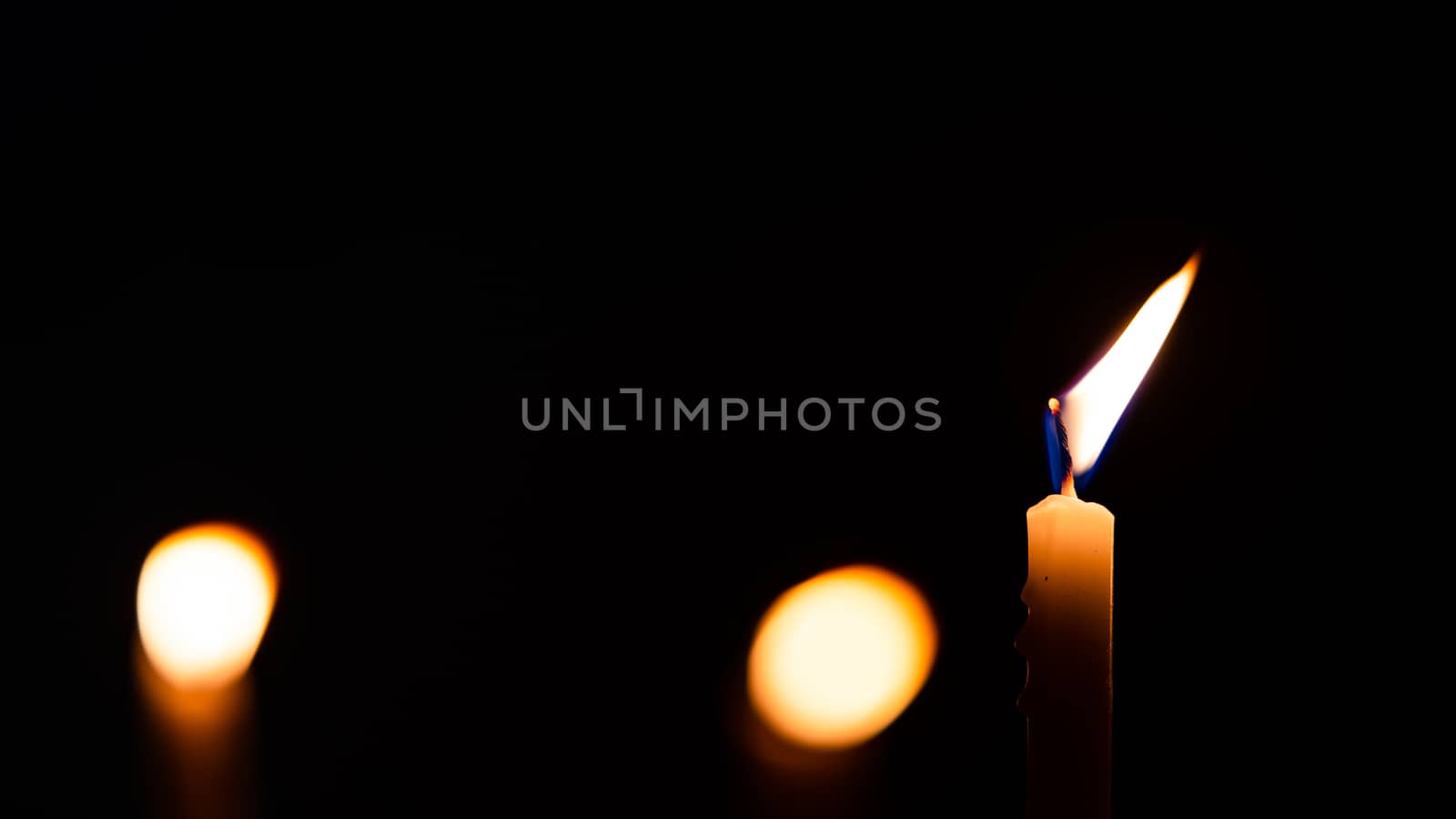 Close-up shots of yellow candles and lights on a black backgroun by ToonPhotoClub