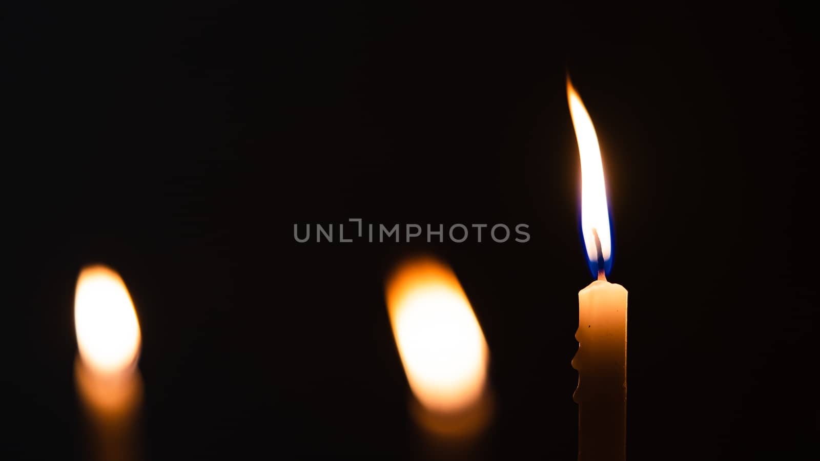 Close-up shots of yellow candles and lights on a black backgroun by ToonPhotoClub