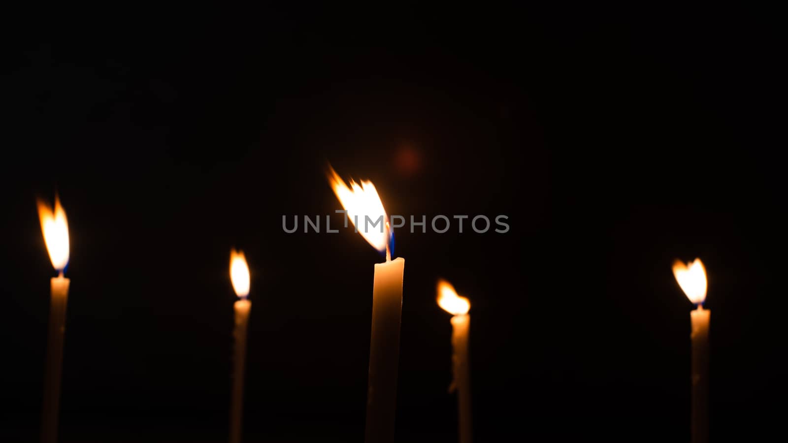 Close-up shots of yellow candles and lights on a black backgroun by ToonPhotoClub