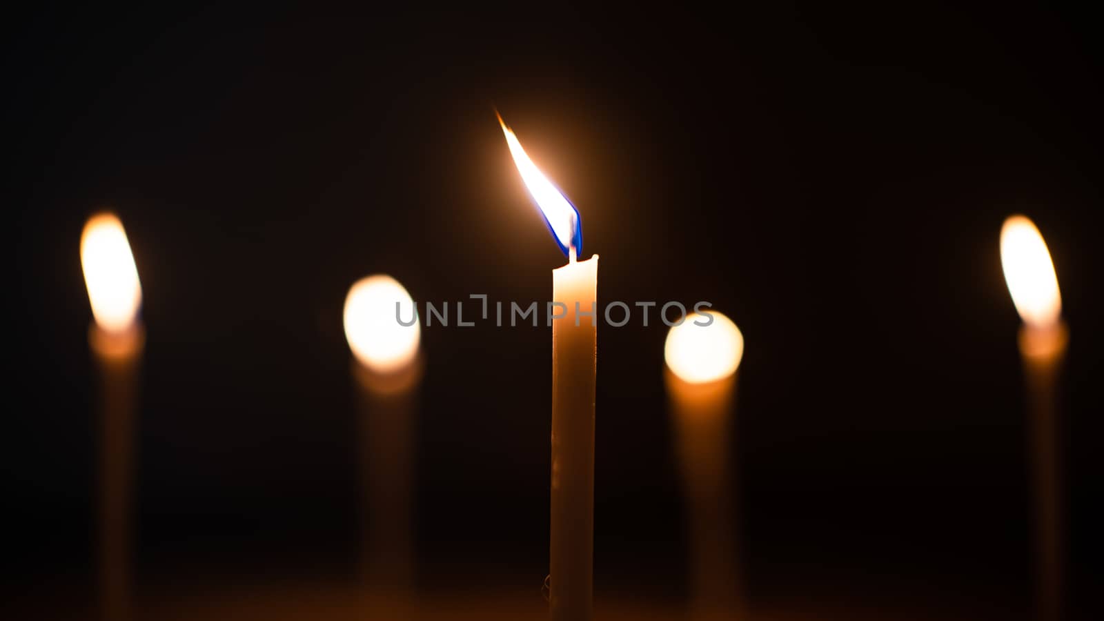 Close-up shots of yellow candles and lights on a black background with bokeh lights