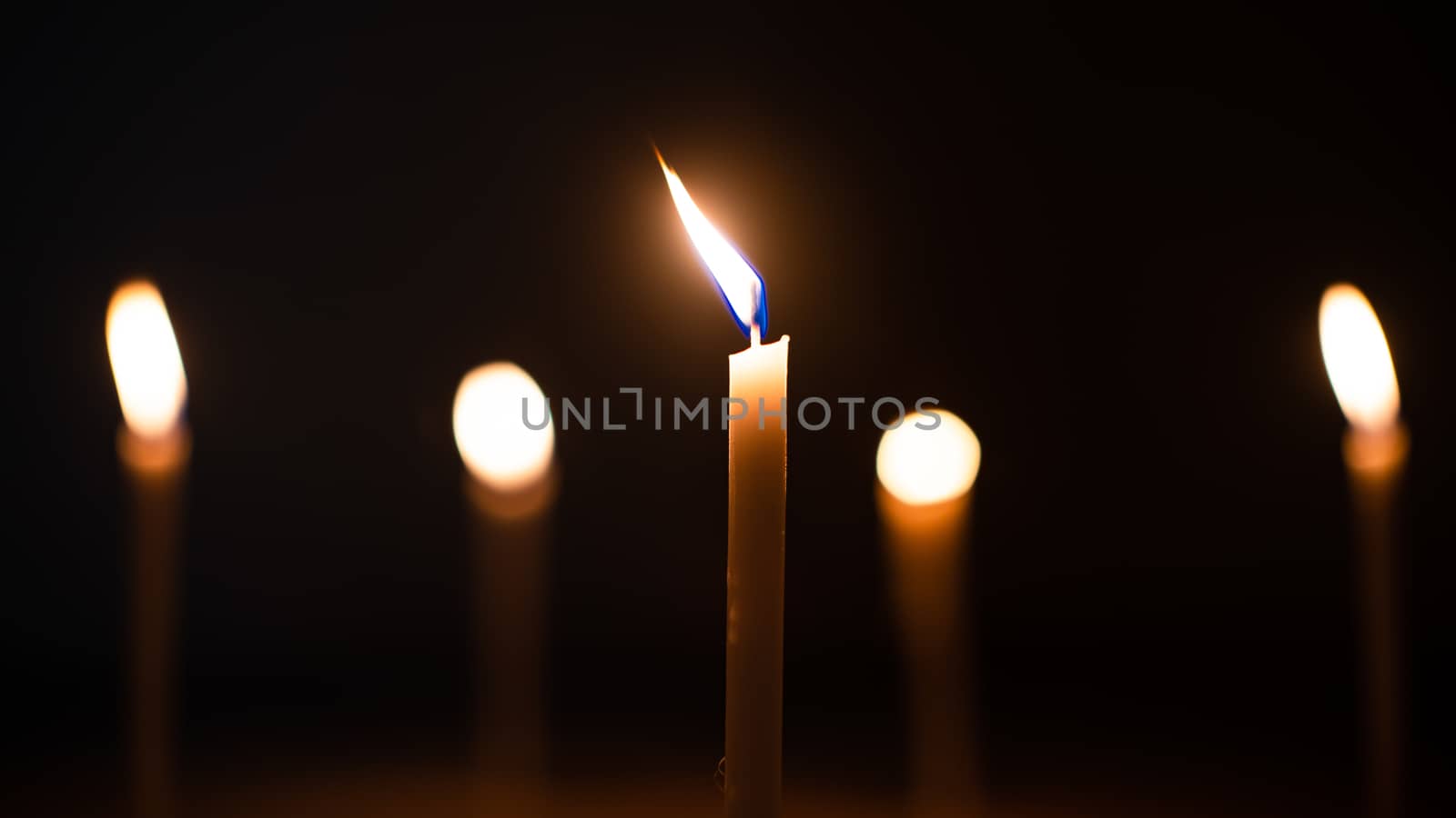 Close-up shots of yellow candles and lights on a black backgroun by ToonPhotoClub