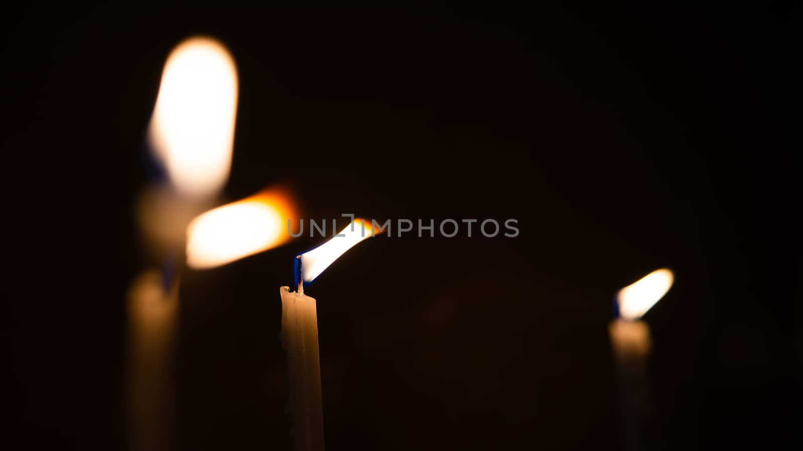 Close-up shots of yellow candles and lights on a black background with bokeh lights