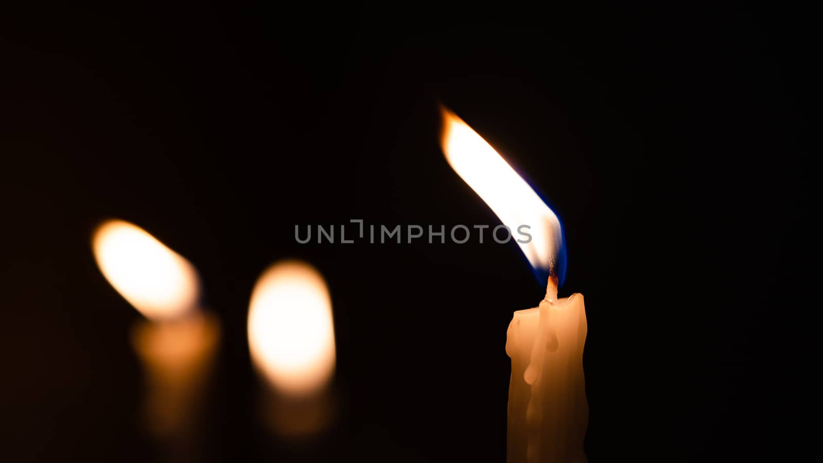 Close-up shots of yellow candles and lights on a black backgroun by ToonPhotoClub