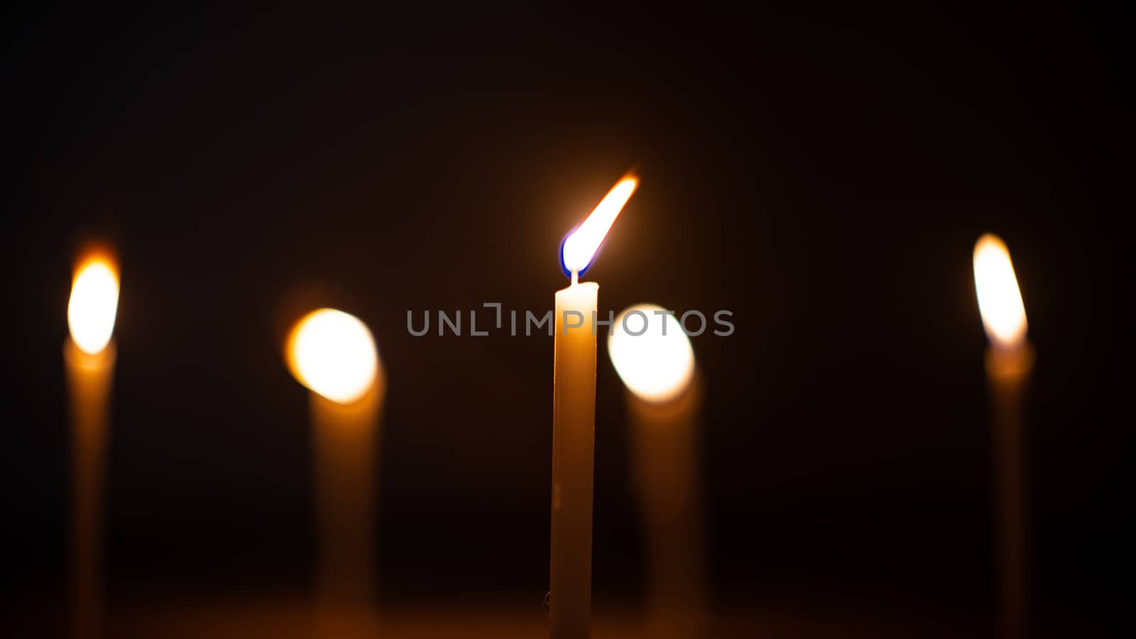 Close-up shots of yellow candles and lights on a black backgroun by ToonPhotoClub