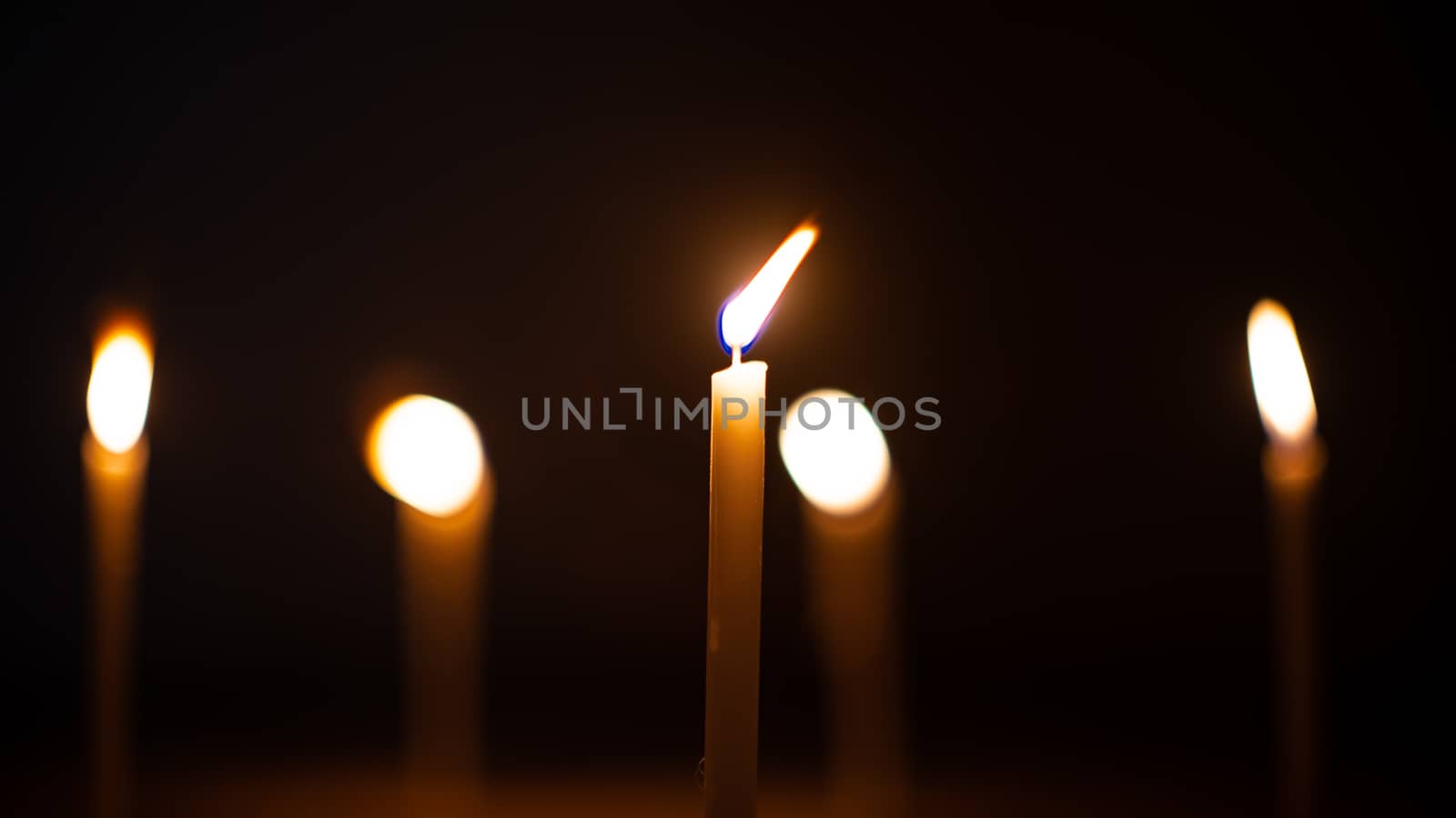 Close-up shots of yellow candles and lights on a black background with bokeh lights