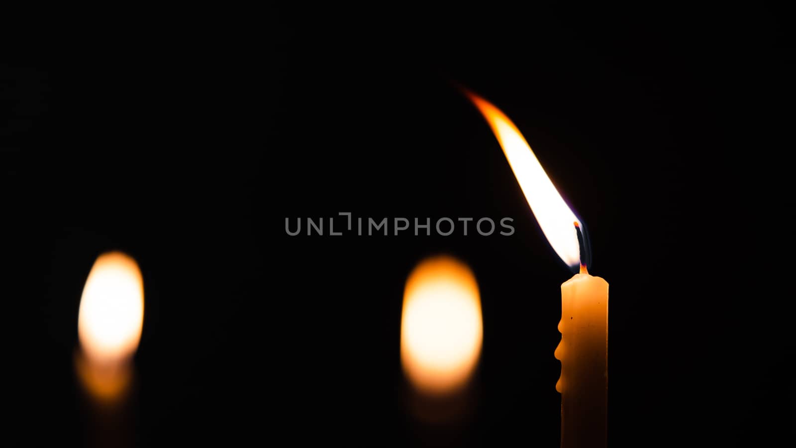 Close-up shots of yellow candles and lights on a black background with bokeh lights