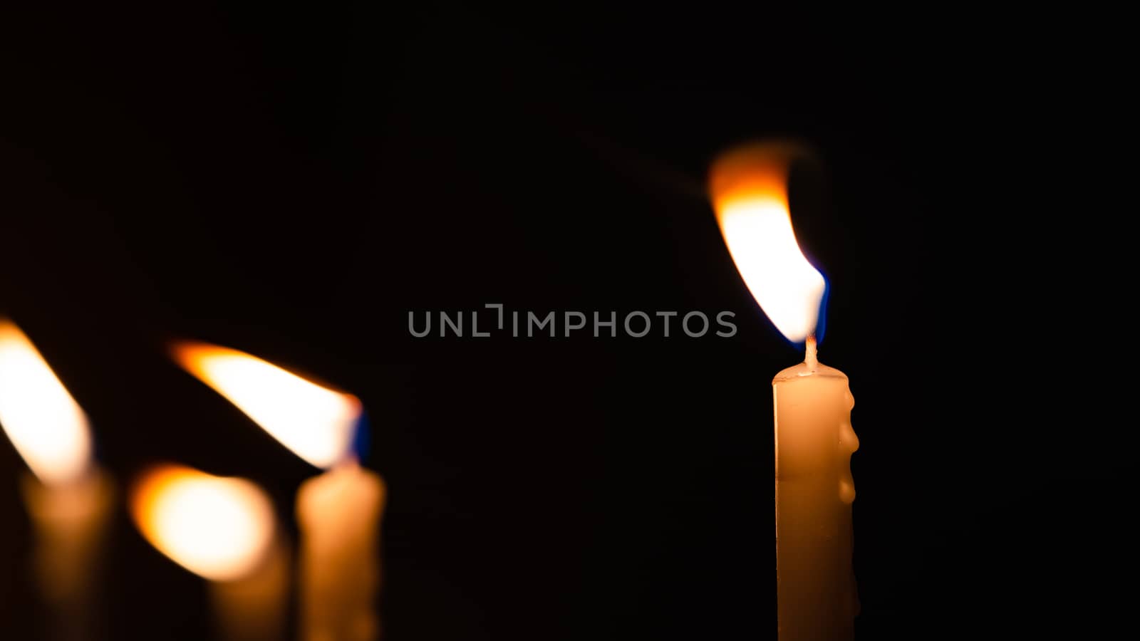 Close-up shots of yellow candles and lights on a black background with bokeh lights