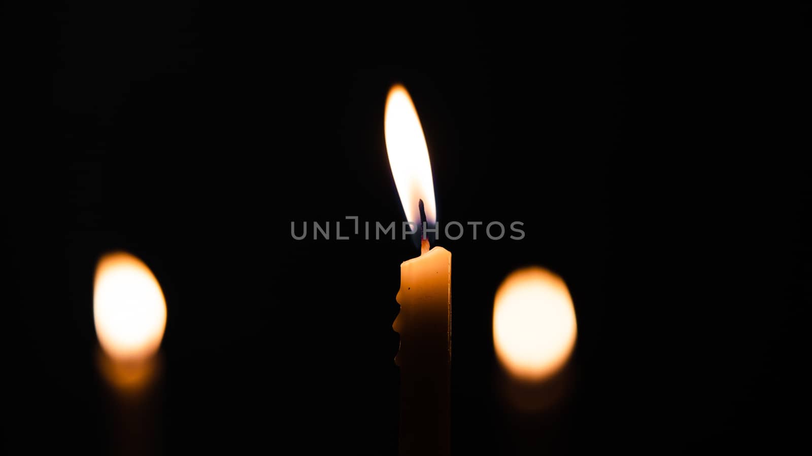 Close-up shots of yellow candles and lights on a black background with bokeh lights