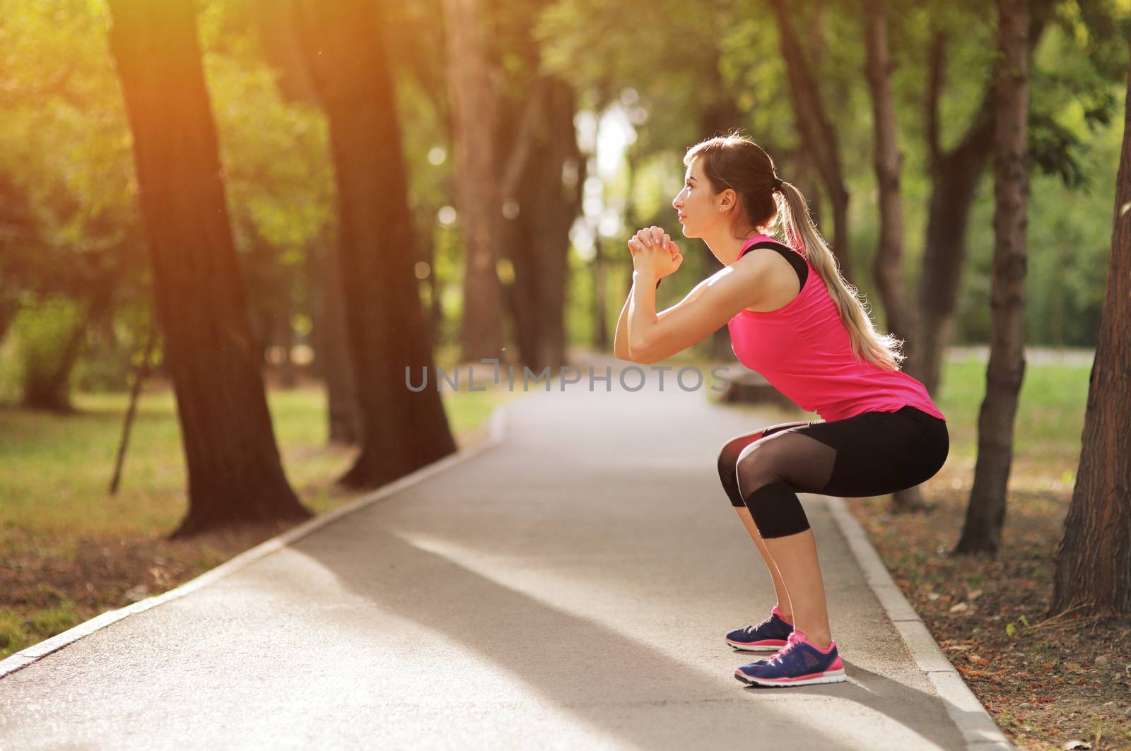 The young woman is engaged in sports fitness in nature forest Healthy fit living. Motivation healthy fit living. Running shoe. Beautiful sunlight. Woman warming up before running. Squats