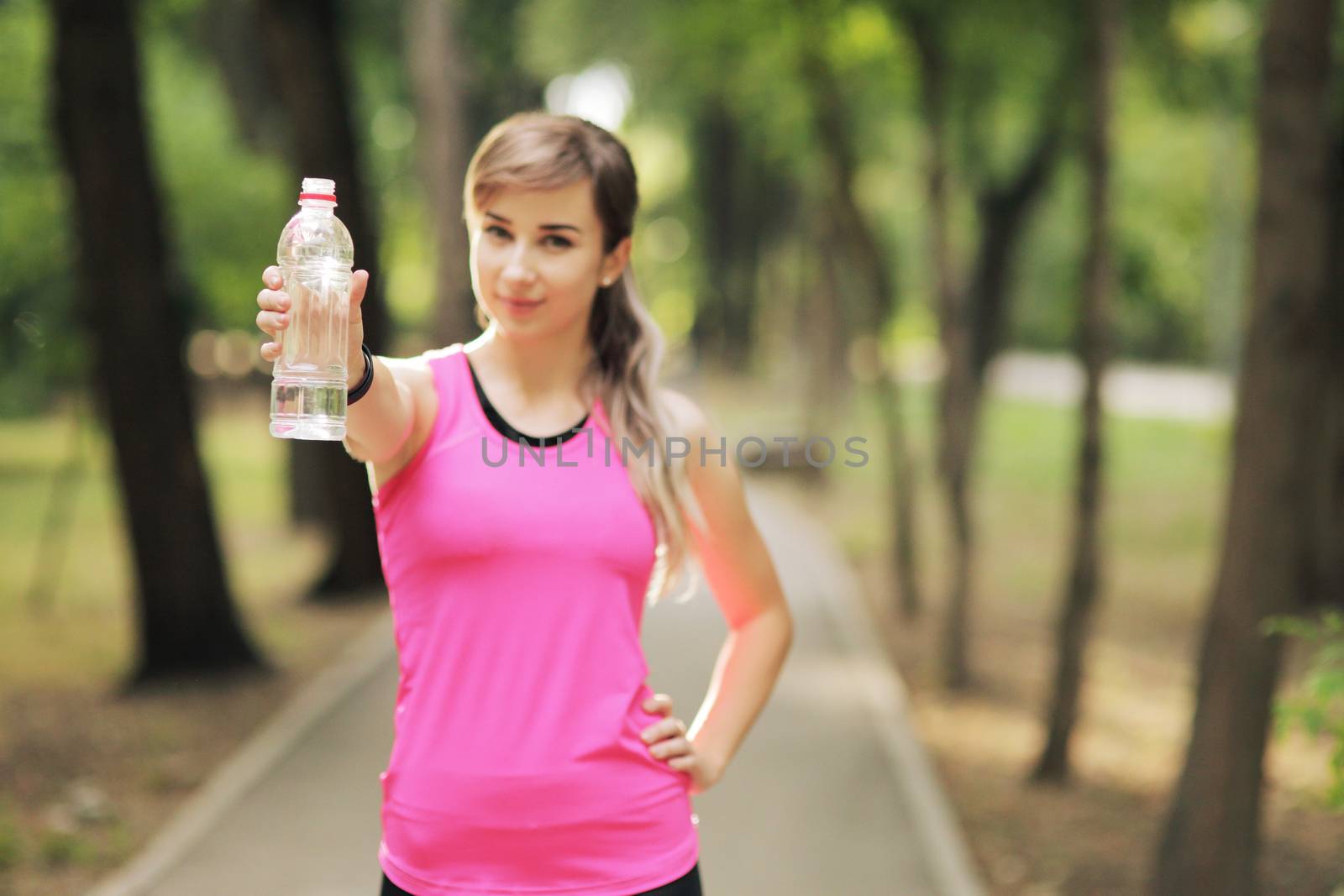 Beautiful fitness athlete runner woman drinking water in the park. Water bottle by selinsmo
