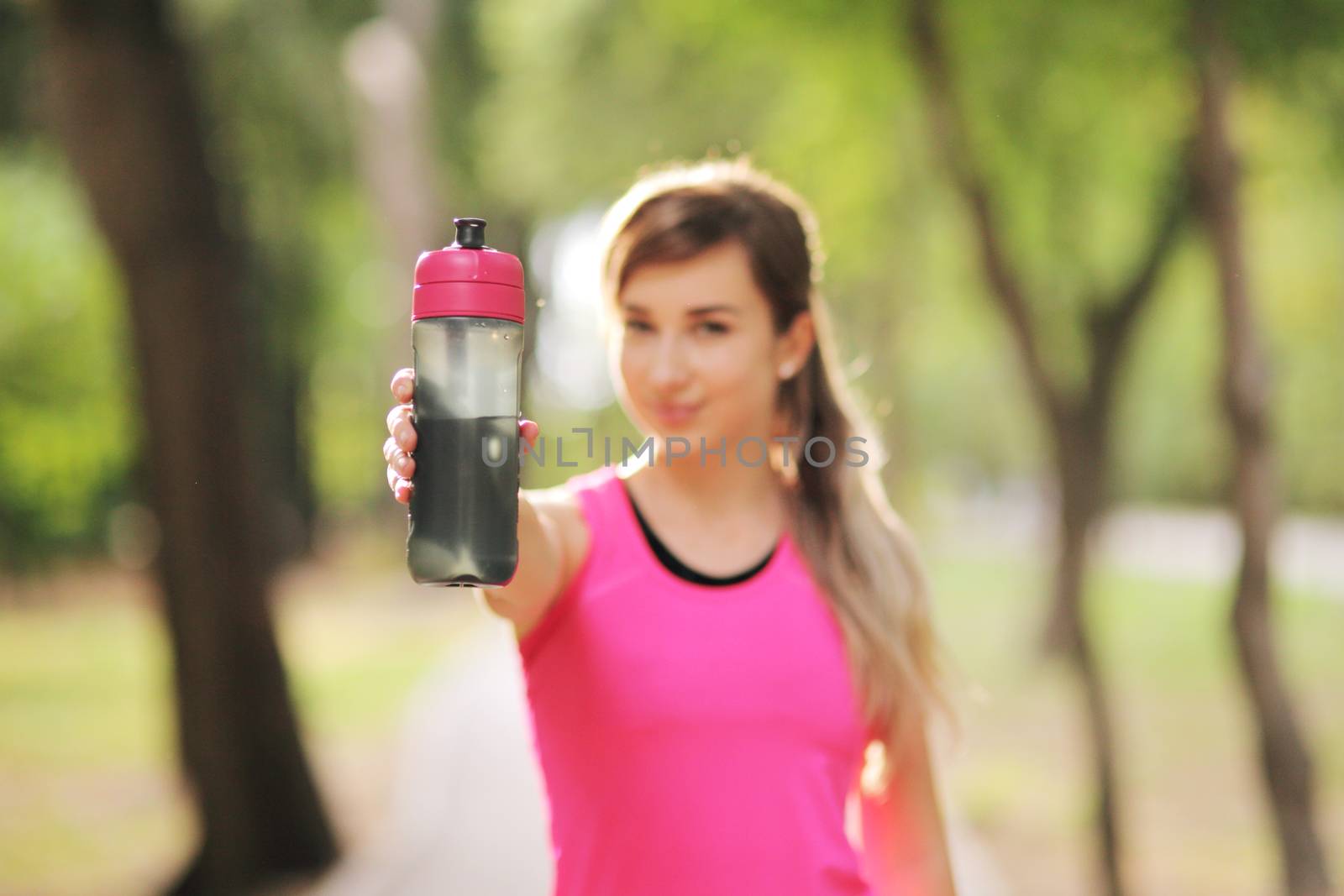 Beautiful fitness athlete runner woman drinking water in the park. Water bottle by selinsmo