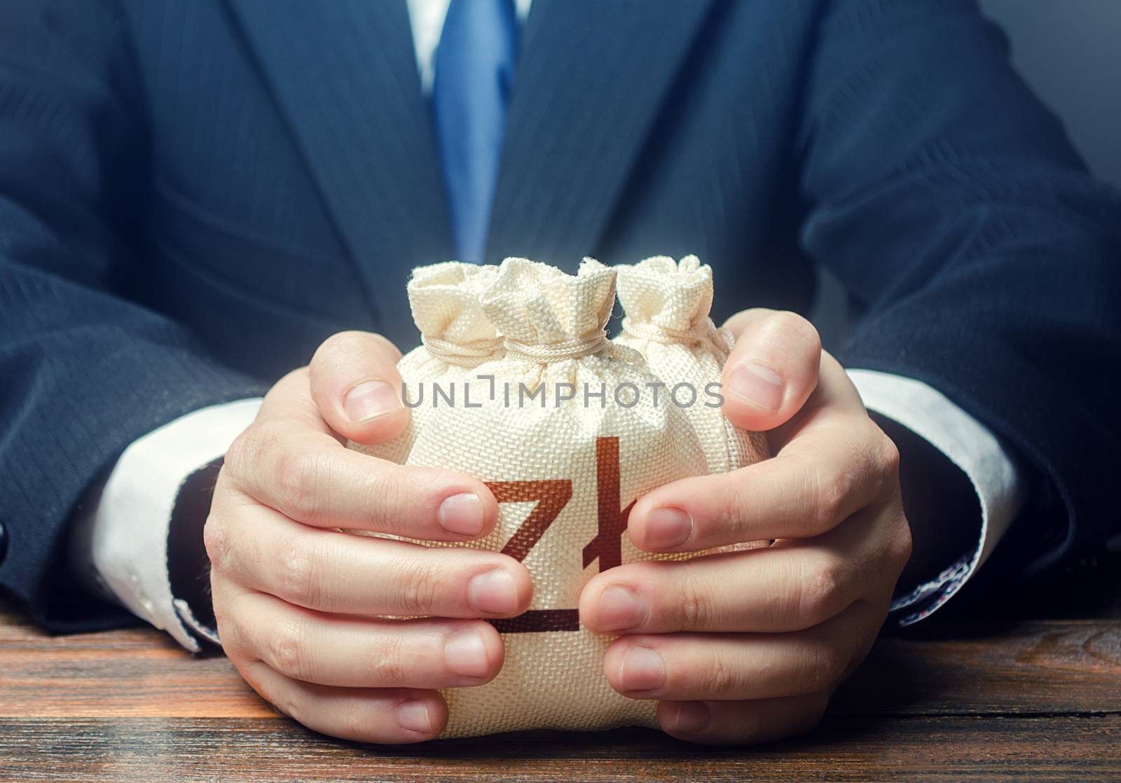 Businessman covers with hands polish zloty money bags. Corrupt schemes. Profit collection and tax withholding. Accumulation of funds, bank loan. Investments. Hit jackpot. Capital. Budget absorption