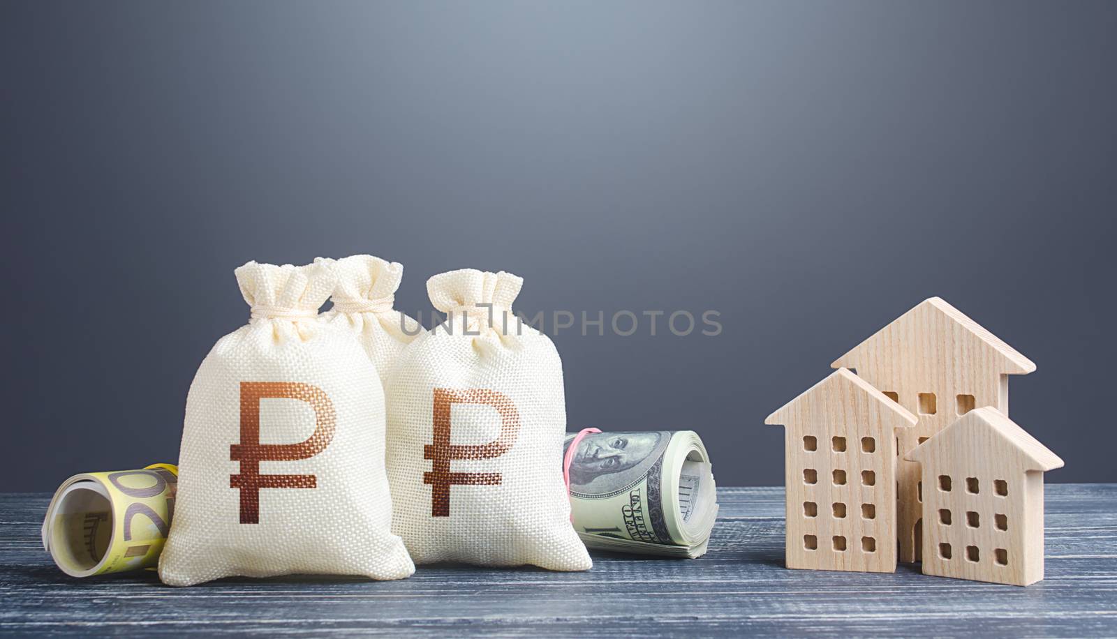 Russian ruble money bags and residential buildings figures. Investments in real estate. Municipal budget management. Taxes. Mortgage loan. Financing the construction and renovation of housing.
