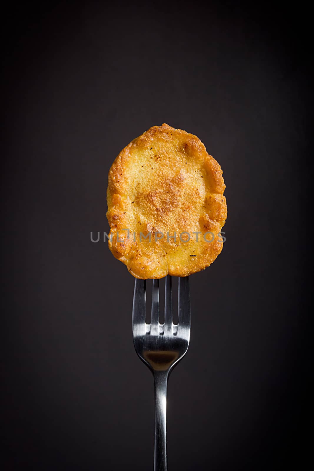 Corn pancakes on a fork on a black background