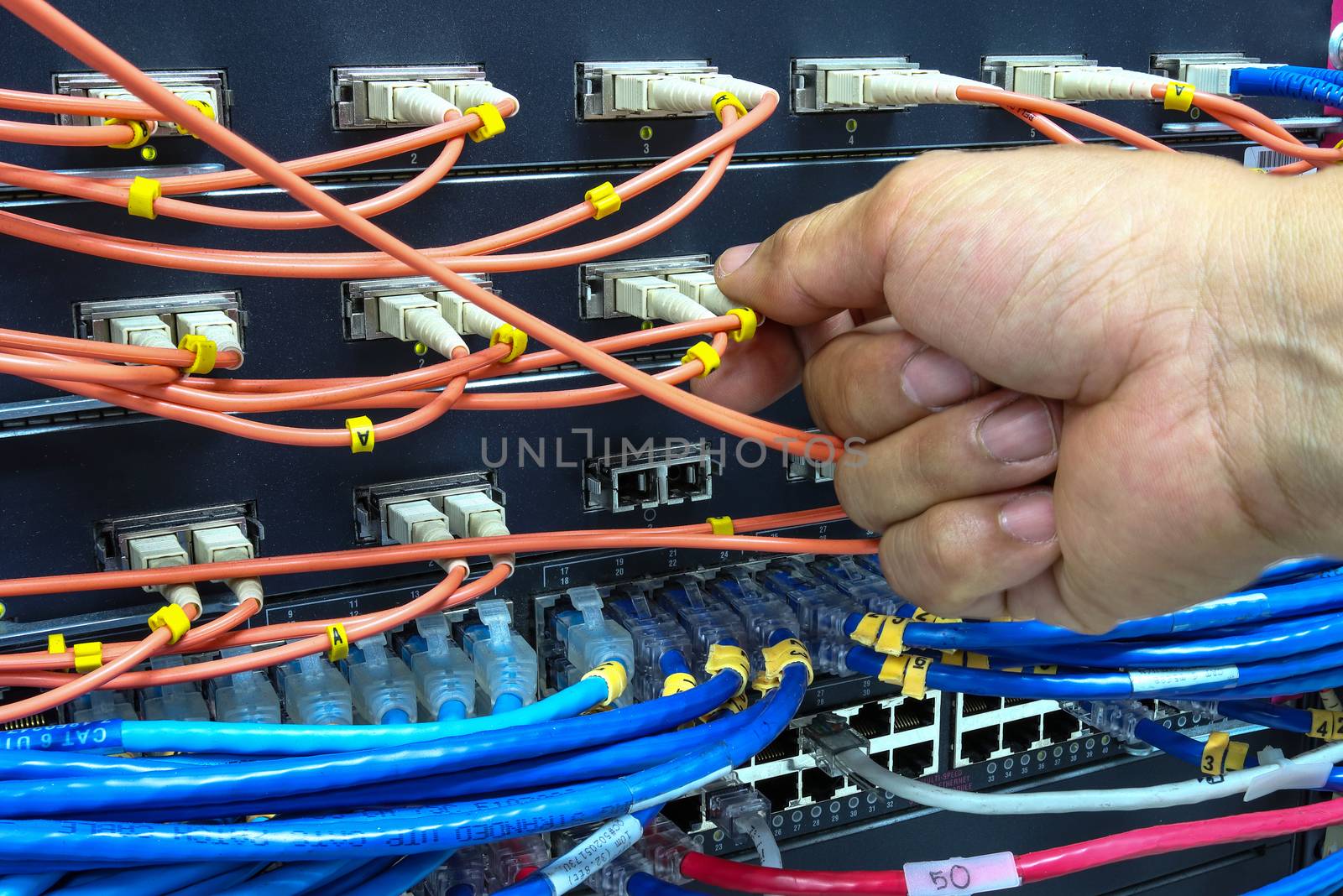 Technician connect fiber cable network to switch port in server room , Concept internet network management

