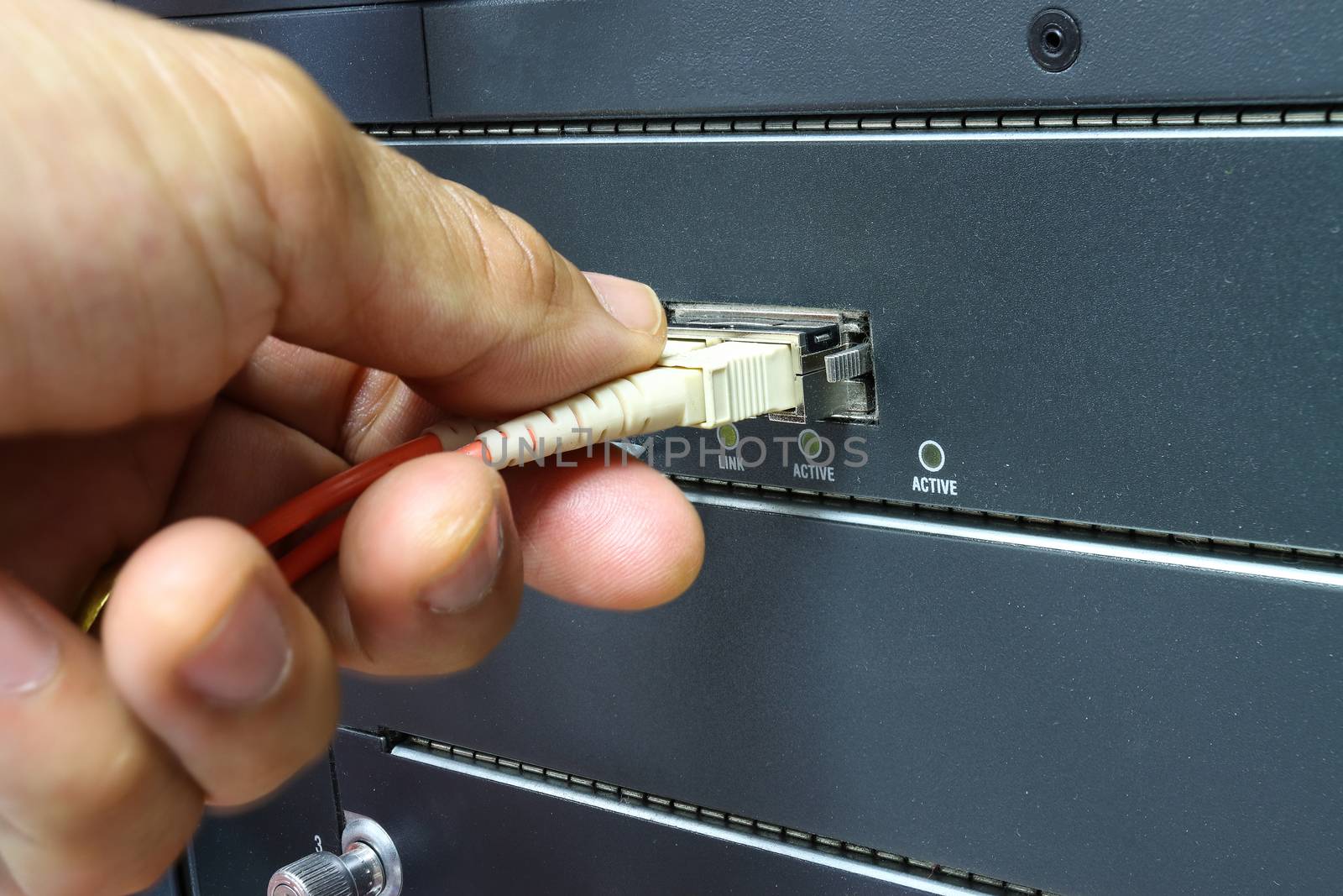 Technician connect fiber cable network to switch port in server room , Concept internet network management
