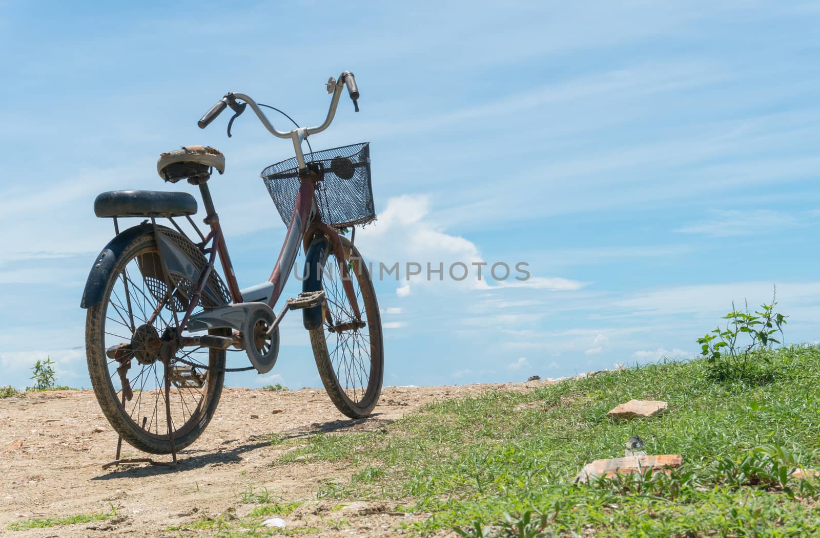 Red bicycle on beach and blue sky and sea or brine. Bicycle on rock or stone mound or pile. Landscape summer concept in relaxation mood for 
design