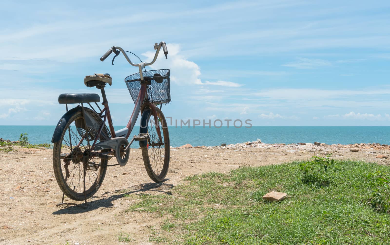 Red bicycle on beach and blue sky and sea or brine. Bicycle on rock or stone mound or pile. Landscape summer concept in relaxation mood for 
design