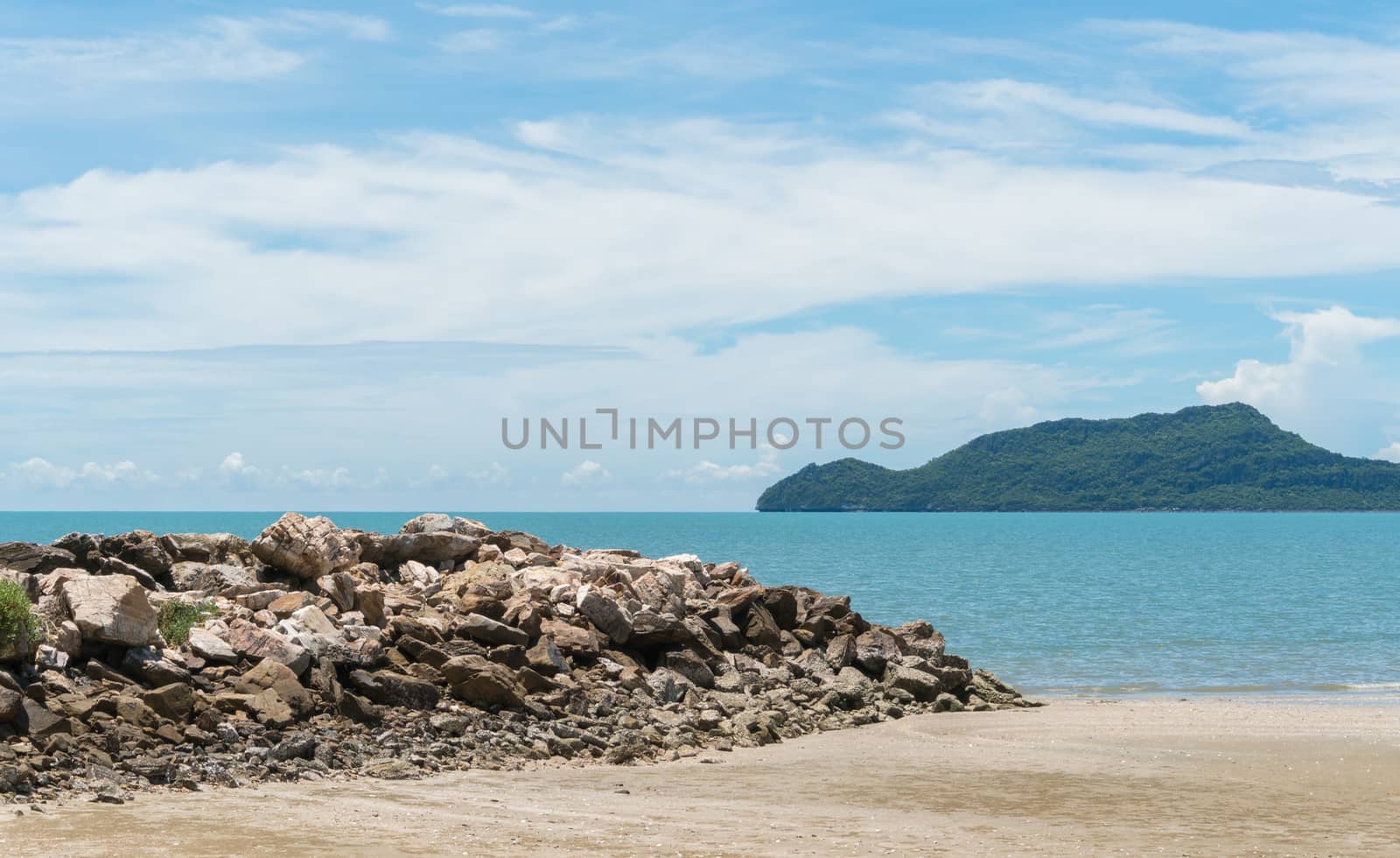 Rock or stone mound or pile on the beach at Prachuap Khiri Khan Thailand. Beach and sea or brine and blue sky and green tree mountain or hill. 
Summer concept in relaxation mood for design