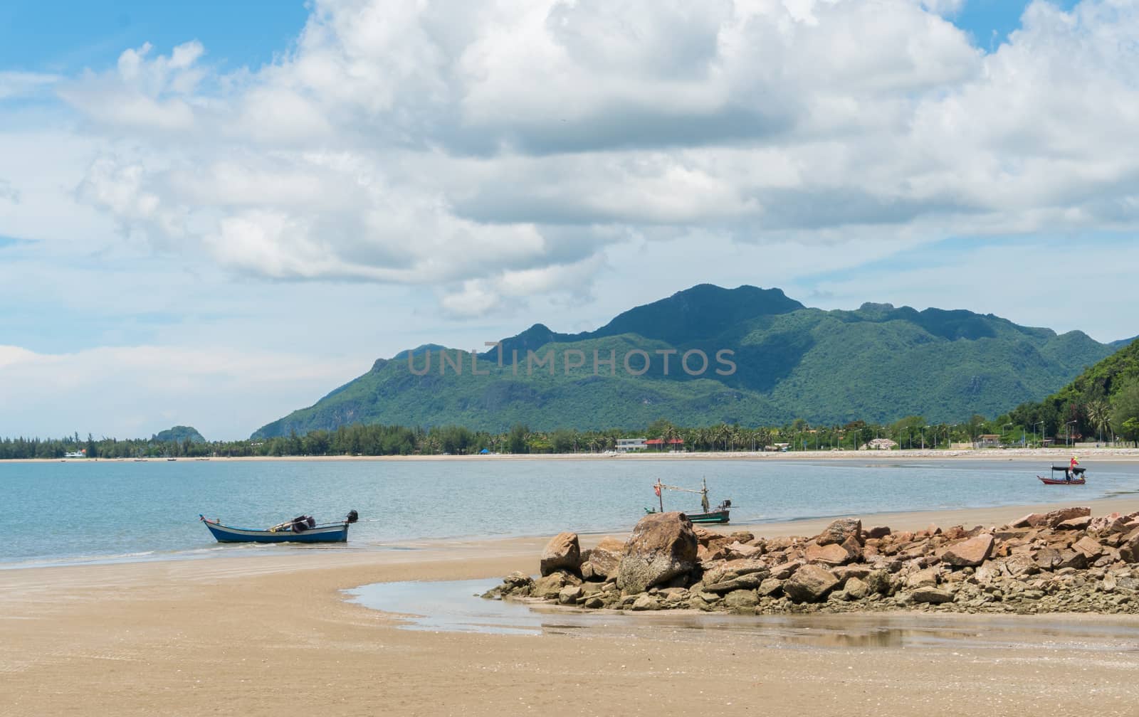 Blue fishing boat on beach and green hill and sea and reef or rock. Fisherman boat or fishing boat for summer concept at Prachuap Khiri Khan 
Thailand