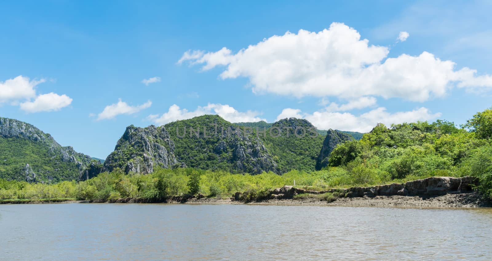 Stone or rock mountain or hill with green tree and blue sky and water and cloud at Khao Dang canal Prachuap Khiri Khan Thailand. Landscape or 
scenery summer concept for boat trip