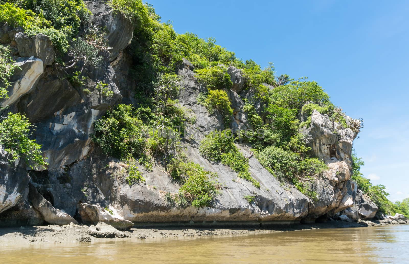 Stone or rock mountain or hill with green tree and blue sky and water and cloud at Khao Dang canal Prachuap Khiri Khan Thailand. Landscape or scenery summer concept for boat trip