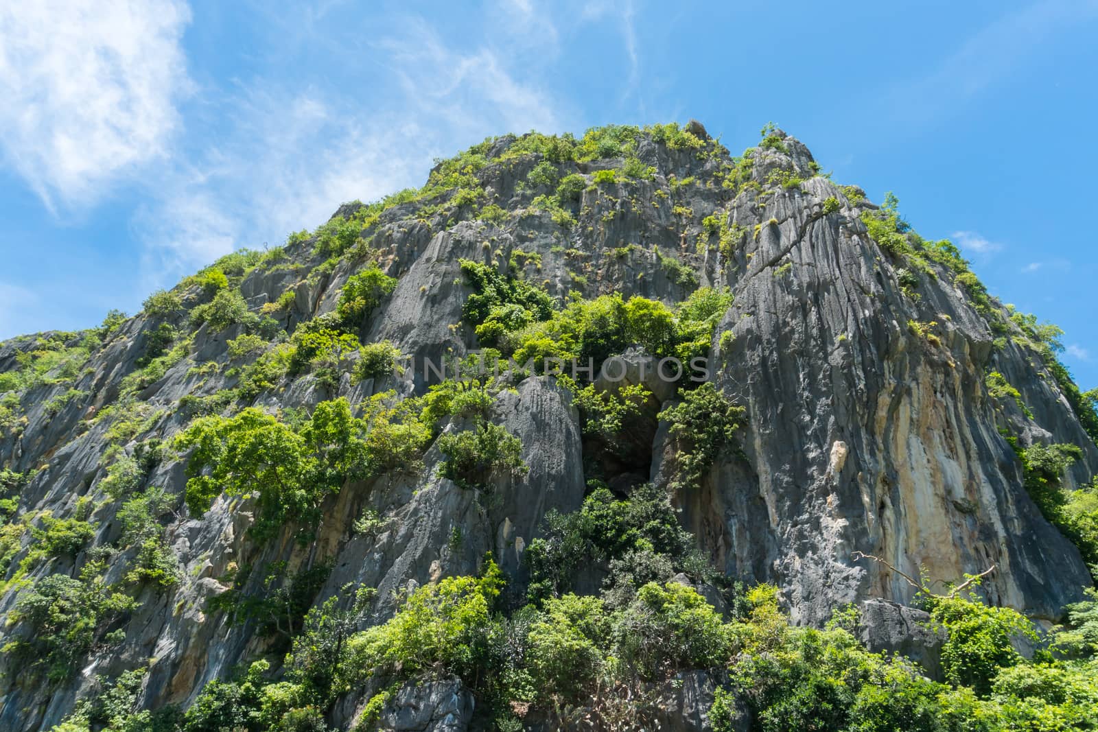 Stone or rock mountain or hill with green tree and blue sky and water and cloud at Khao Dang canal Prachuap Khiri Khan Thailand. Landscape or scenery summer concept for boat trip