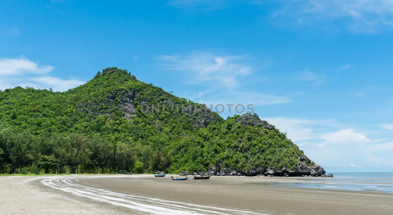 Rock or stone mountain or hill and blue sky and fishing boat at Sam Phraya beach Prachuap Khiri Khan Thailand. Landscape or scenery in 
natural for summer concept