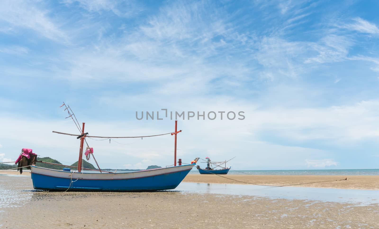 Blue fishing boat or fisherman boat or ship on Sam Roi Yod bech Prachuap Khiri Khan Thailand with blue sky and cloud and blue sea and 
mountain or hill. Landscape or scenery for summer season concept