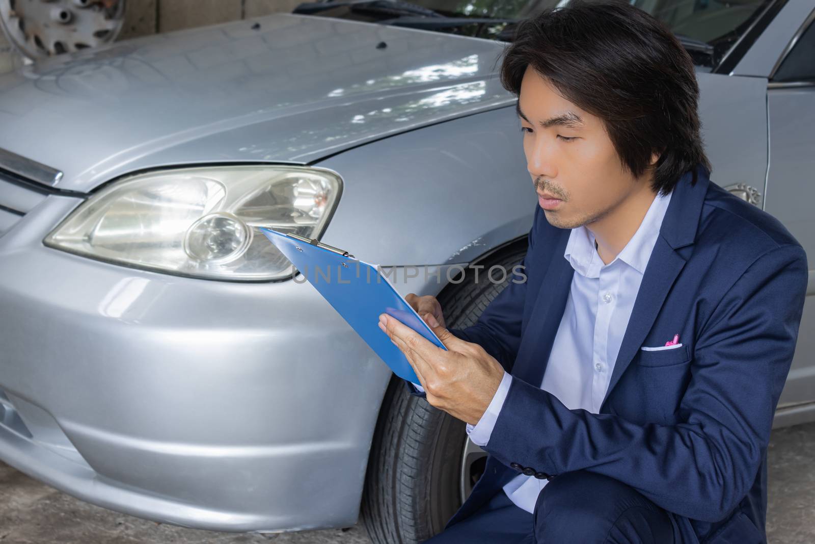 Asian Insurance Agent or Insurance Agency in Suit Reading Report and Inspecting Car Crash from Accident for Claim at Outdoor Place