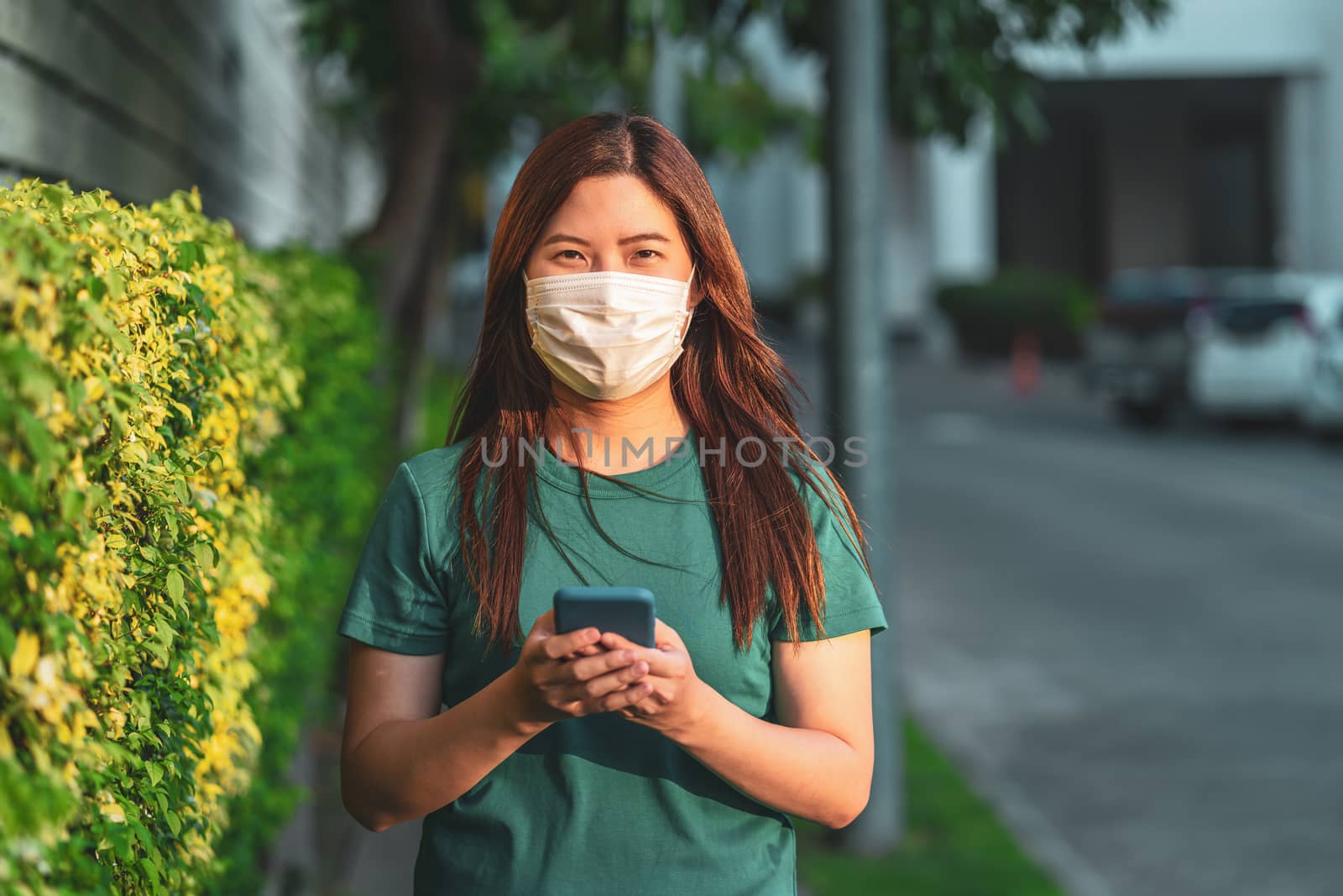 Asian woman hand using smart mobile phone with safety medical face mask for prevent Coronavirus or Covid19 Outbreak when travel to work in home or aaprtment area for self isolate, infection concept