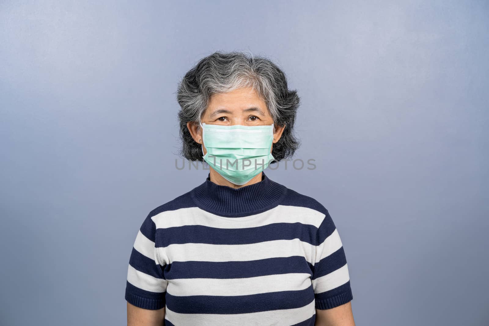 Portrait of asian old woman wearing face surgical mask on blue color background, Coronavirus pandemic, covid19 outbreak, social distancing and responsibility, protection against virus concept