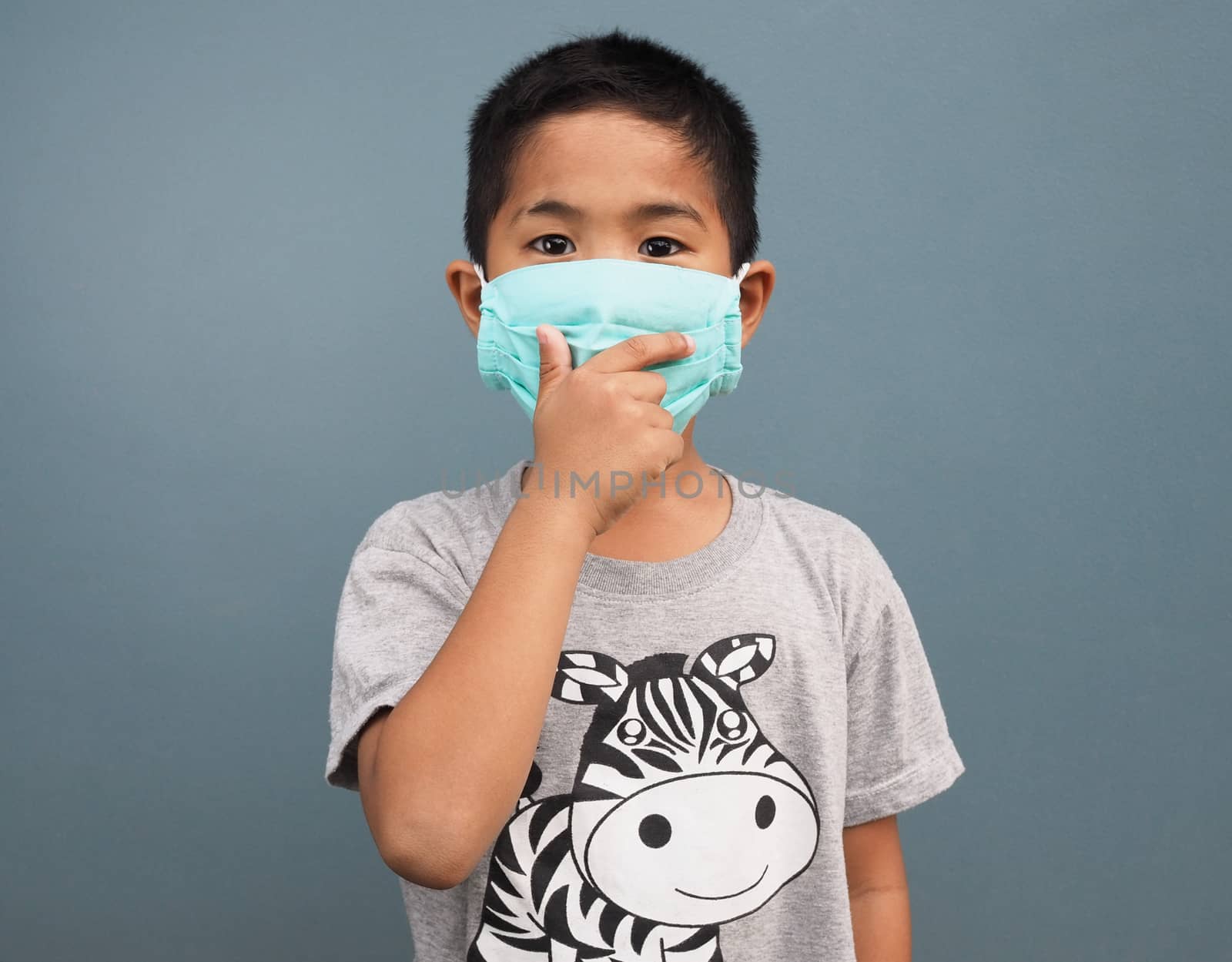 A boy wearing a protective mask While covering his hand while coughing.