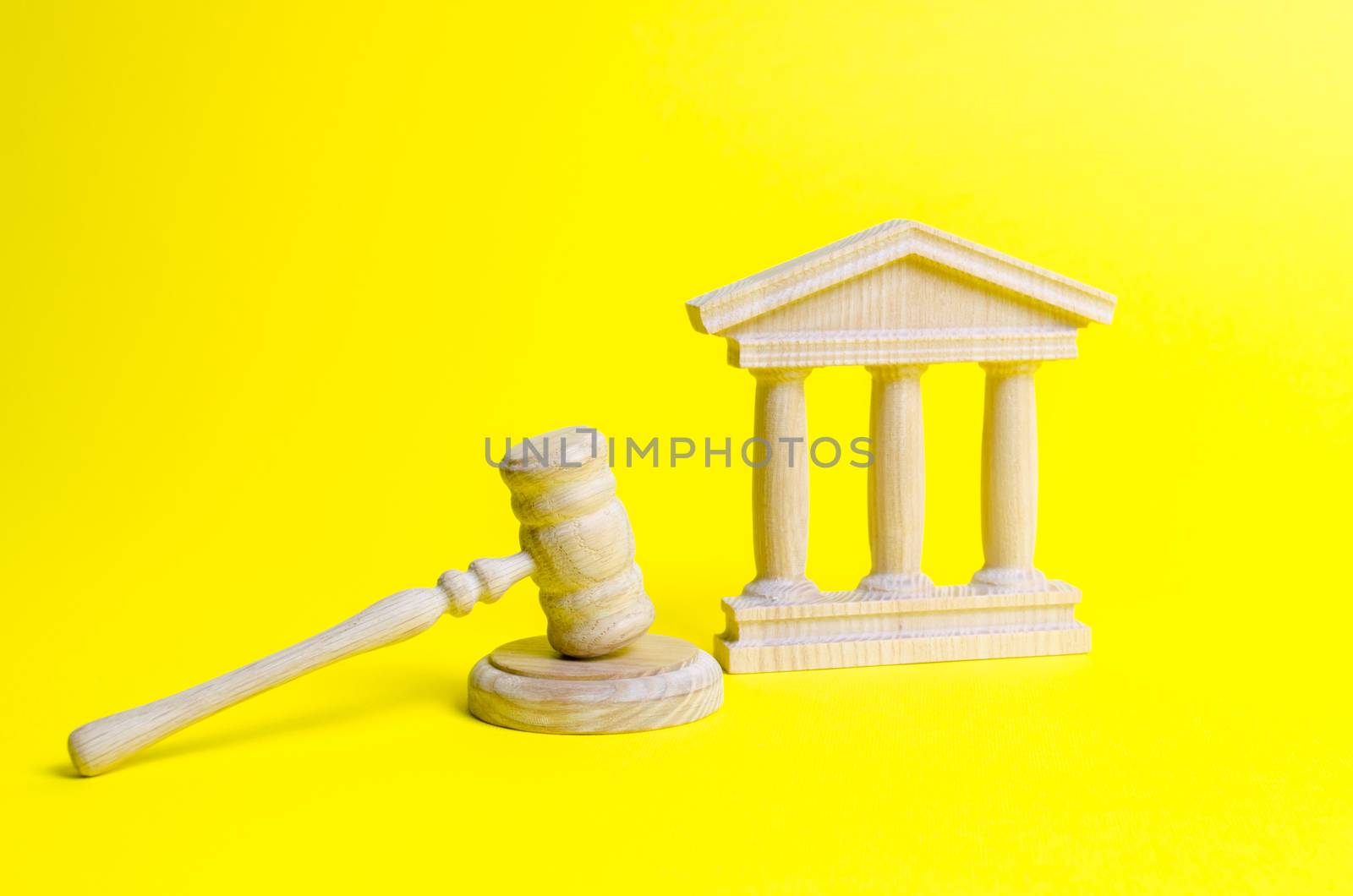 Wooden judge hammer and government building on a yellow background. Court. Concept of the state judicial system. Prohibitions and criminalization, repression, restriction of freedoms and rights