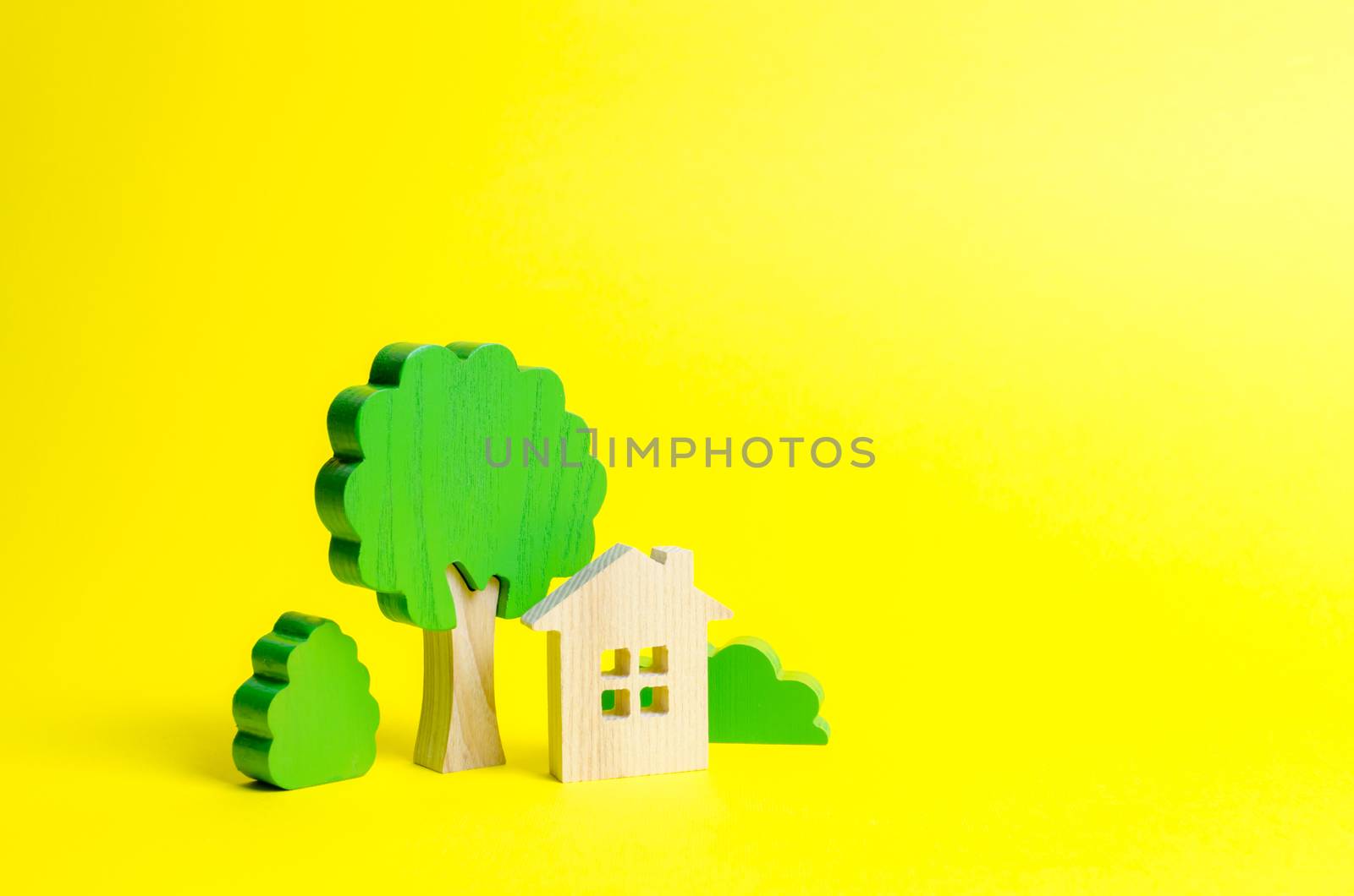 Large two-story house surrounded by bushes and trees on an yellow background. Urbanism and urban landscaping. Acquisition of affordable housing in a mortgage. Accommodation for families.