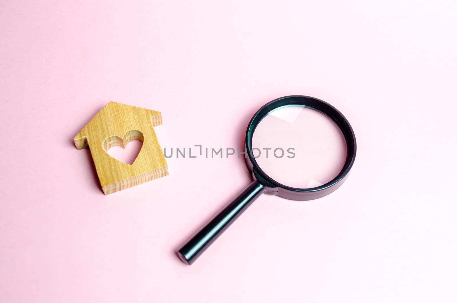 Wooden house with a heart and a magnifying glass. Search and purchase of affordable housing for young families and married couples. Mortgage. Rent a home for a romantic holiday on Valentine's Day.
