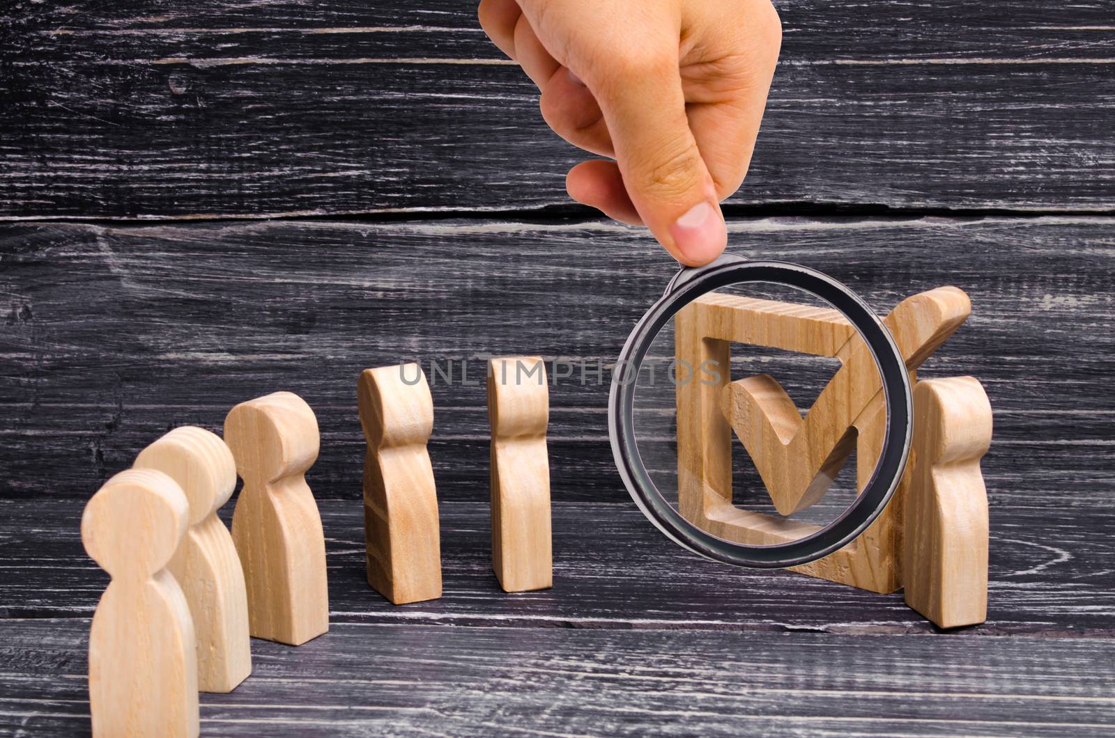 Magnifying glass is looking at the Live line of people is standing together to a tick in the box. The concept of elections and social technologies. Volunteers, parties, candidates. Human rights.